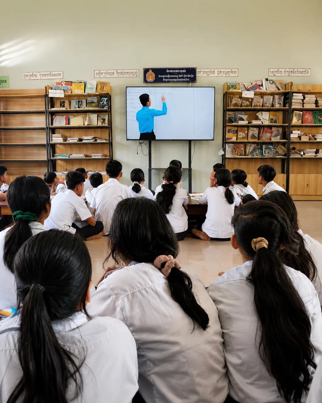 Students in a remote Cambodian school classroom watching an English lesson on a smart TV installed by Khmer Khom
